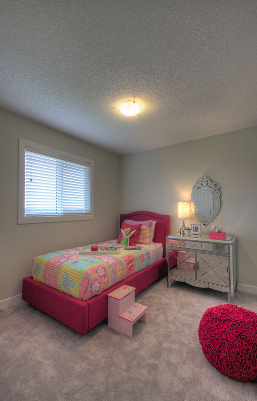 Bedroom woth pink twin bed and a small steel reflective vanity in the Banbury II model home.