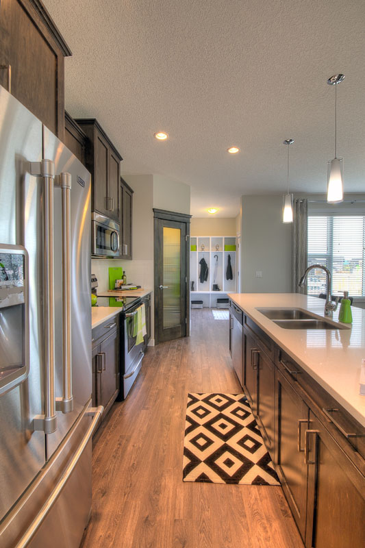 Galley view of the kitchen with diamond print mat and green accent towel and soap dispenser in the Banbury II model home.
