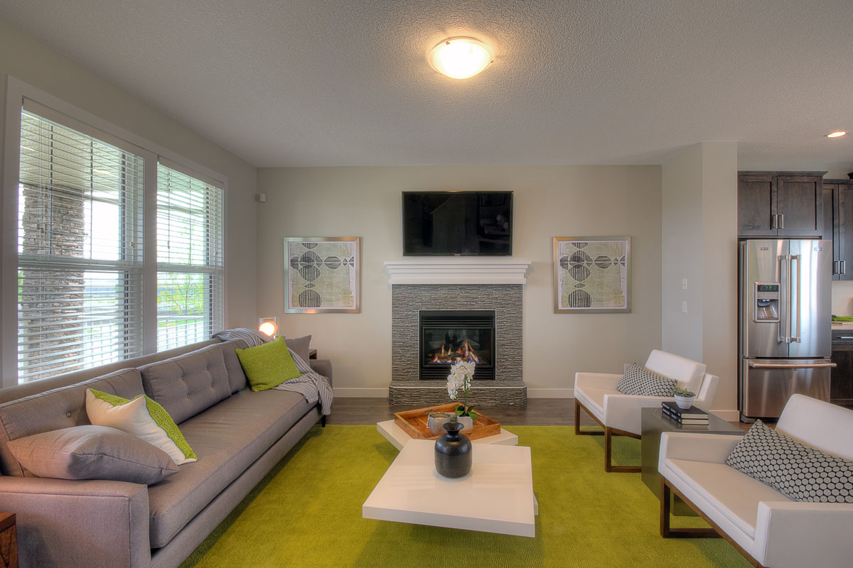 living room with lit fire place and green area rug in the Banbury II model home from Nuvista Homes.