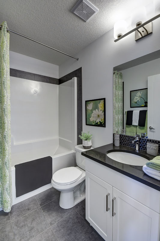 Basement bathroom with green shower curtian and white vanity in the Banbury II home from Nuvista Homes.