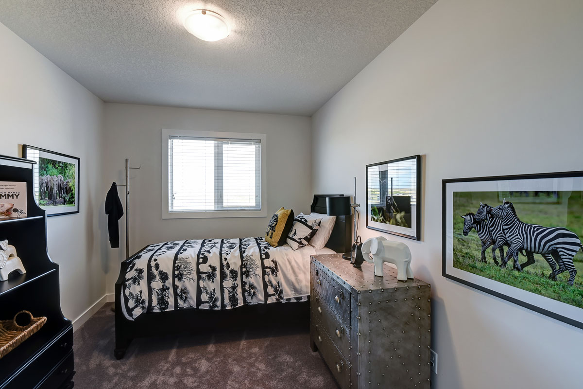 Bedroom with queen size bed and industrial designed dresser in the Banbury II model home from Nuvista Homes.