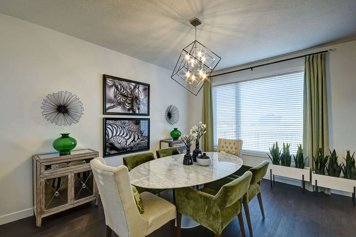 Dining room with oval marble table and 4 swede green shairs and 2 white head chairs in the Banbury II model home from Nuvista Homes.