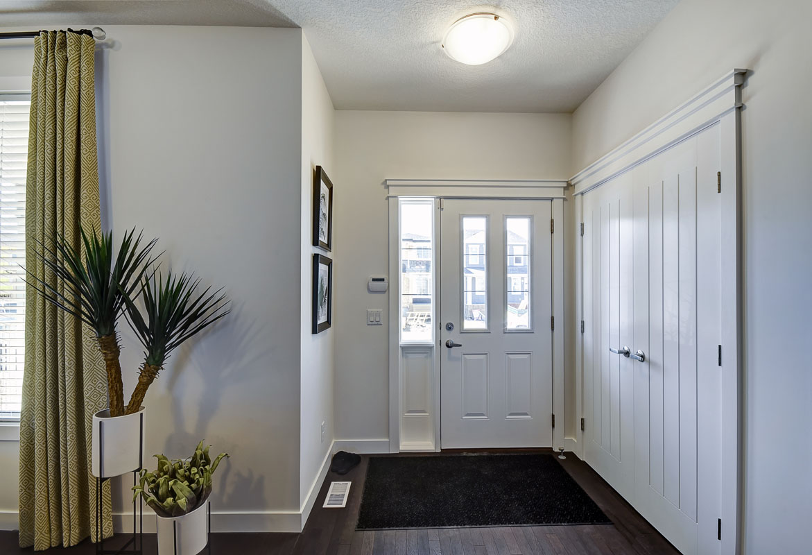 Foyer of the Banbury II model home from Nuvista Homes with green curtians and a black floor matt.