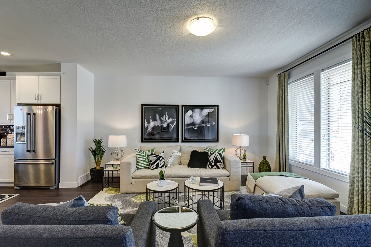 Main living room with beige couch and two blue chairs in the Banbury II model home from Nuvista Homes.