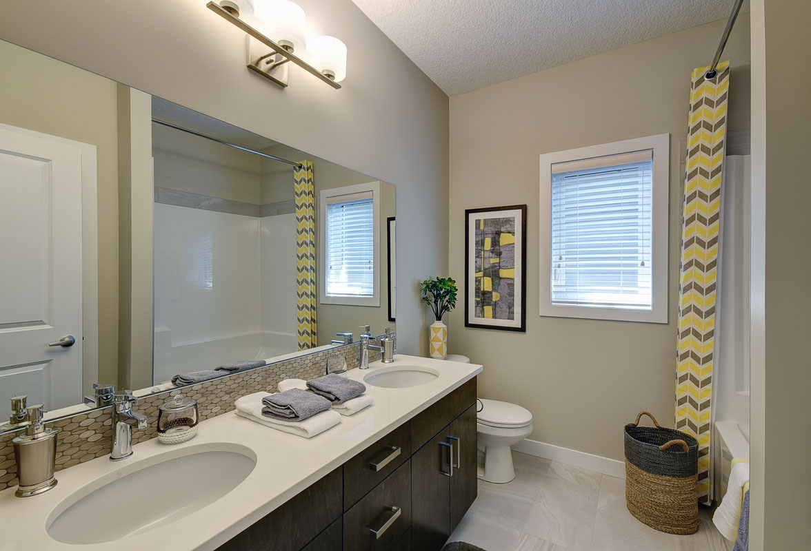 bathroom with yellow chevron shower curtian and double vanity next to toliet in the Bentley II model home.