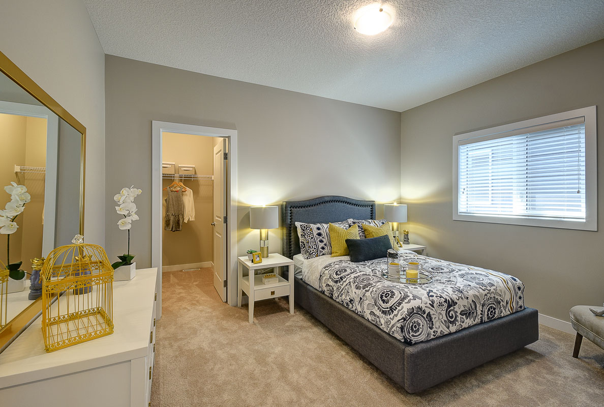 Bedroom one in the Bentley II model home with twin bed on grey bed frame with white dresser and matching nightstands.
