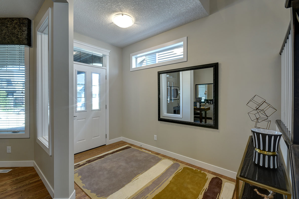 Main foyer in the Bentley II model home with large modern area rug and mirror on the wall.