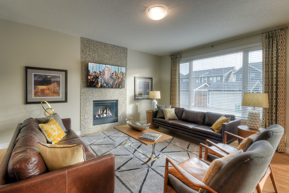 Great room in the Bentley II model home with two leather couchs and two matching modern wood chairs.
