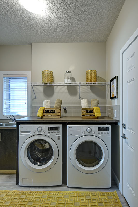 Laundry room with matching white LG washing machines next to yellow rug in the Bentley II model home.