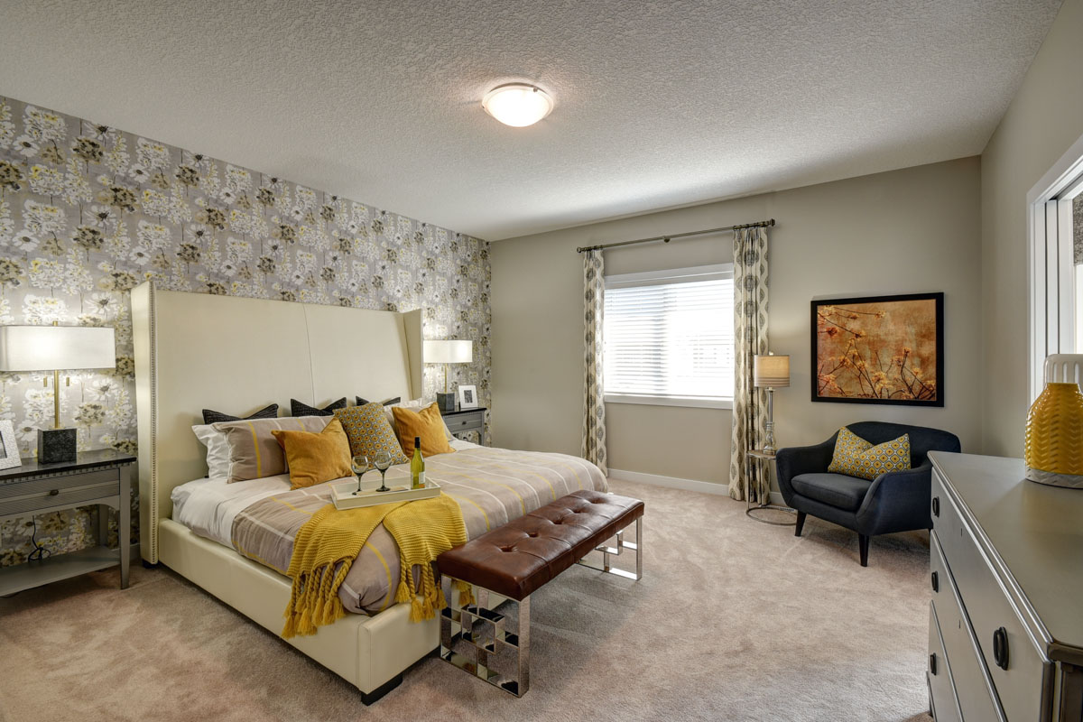 Master bedroom with king size bed in front of yellow and white accent wall in the Bentley II model home.