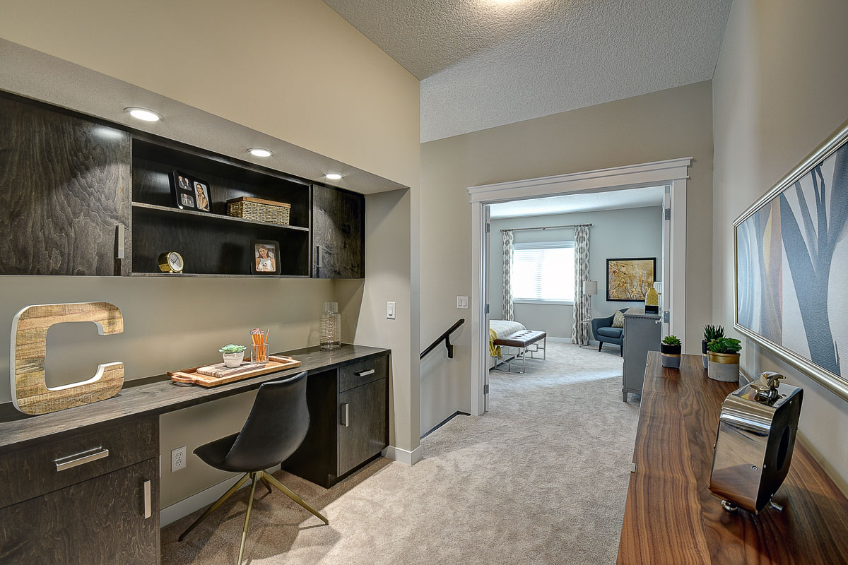 Small pocket office upstairs in the Bentley II model home with built in desk and light grey carpet flooring.