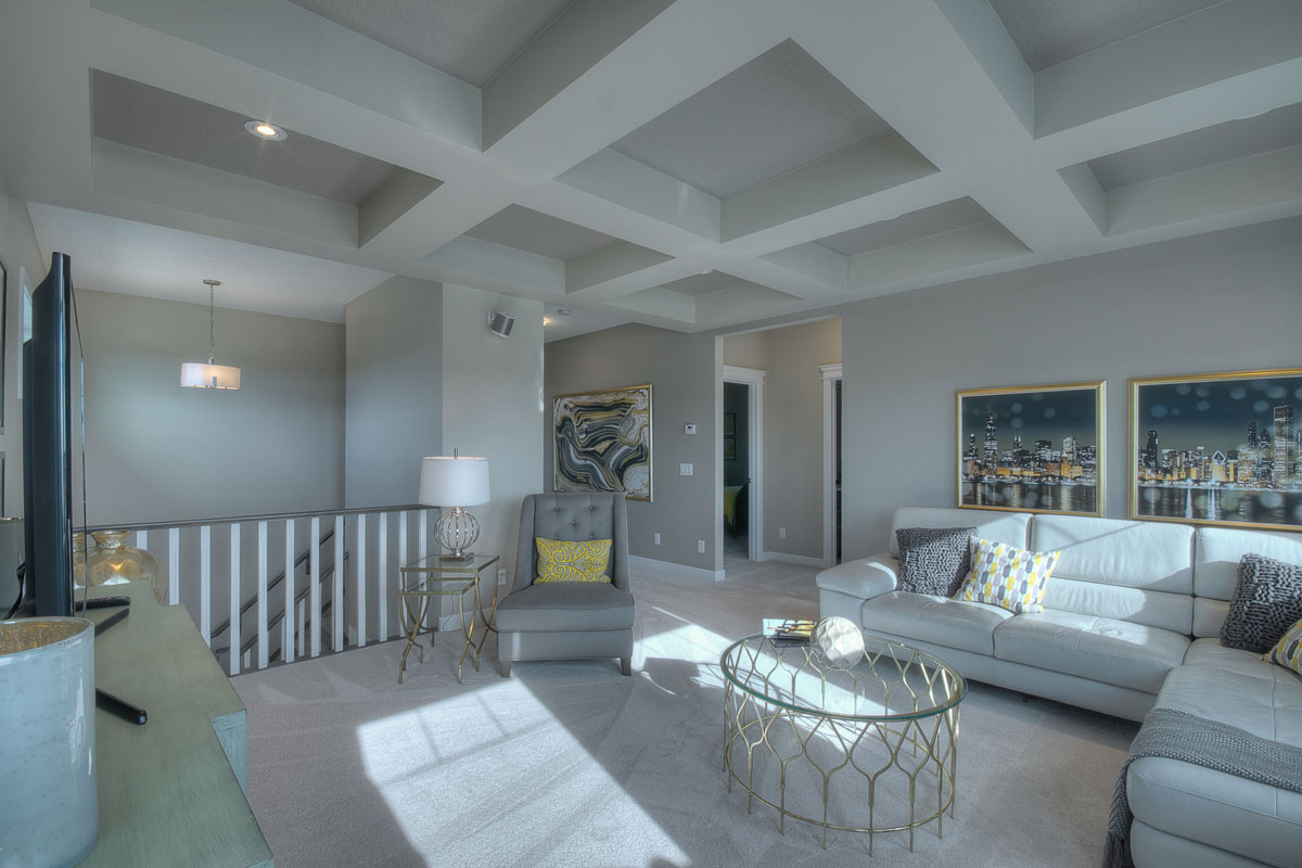 Upstairs bonus room in the Bentley II model home with large light blue sectional across from entertainment center.