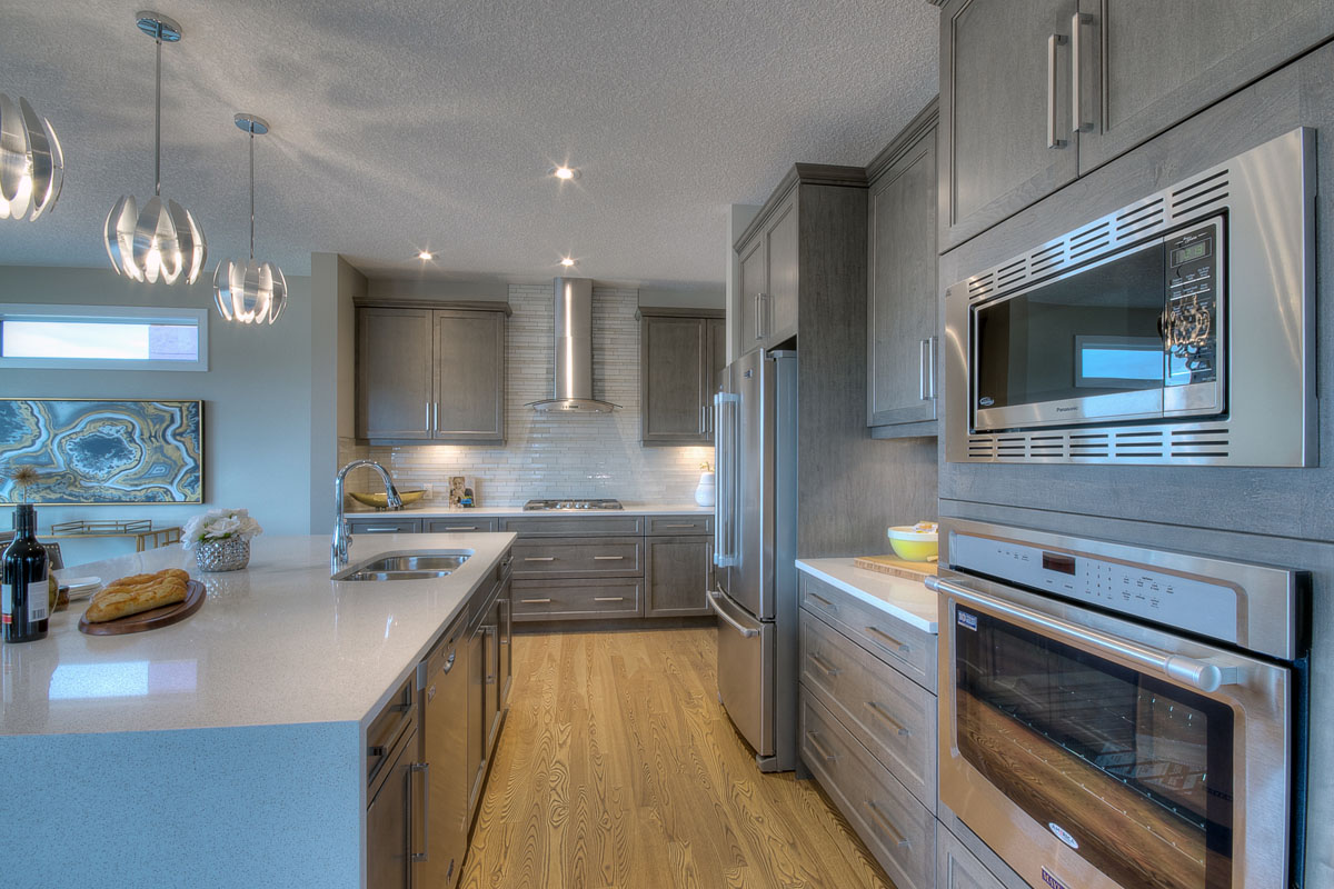 Kitchen with light grey cabinets and stacked oven and microwave in the Bentley II model home.