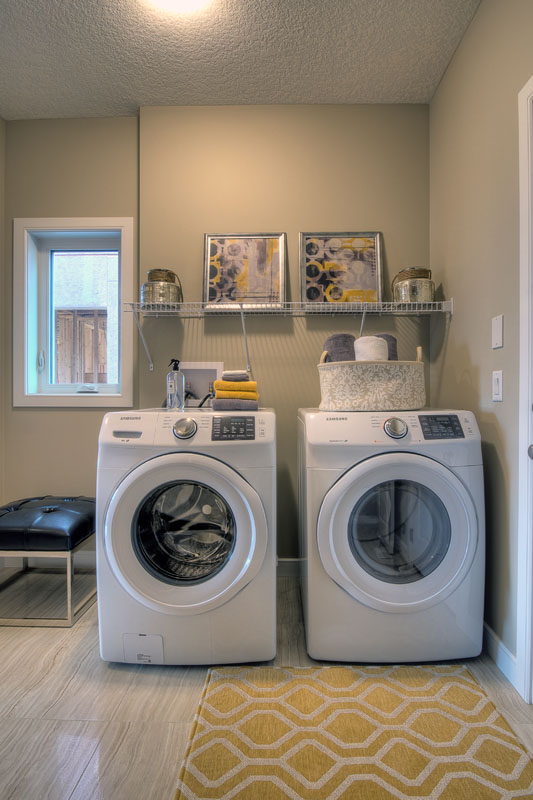 Laundry room with two white LG washing machines and a yellow mat in the Bentley II model home.