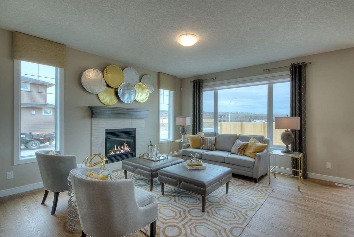 Living room with fire place and ligth grey sofa across from two matching grey chairs in the Bentley II model home.