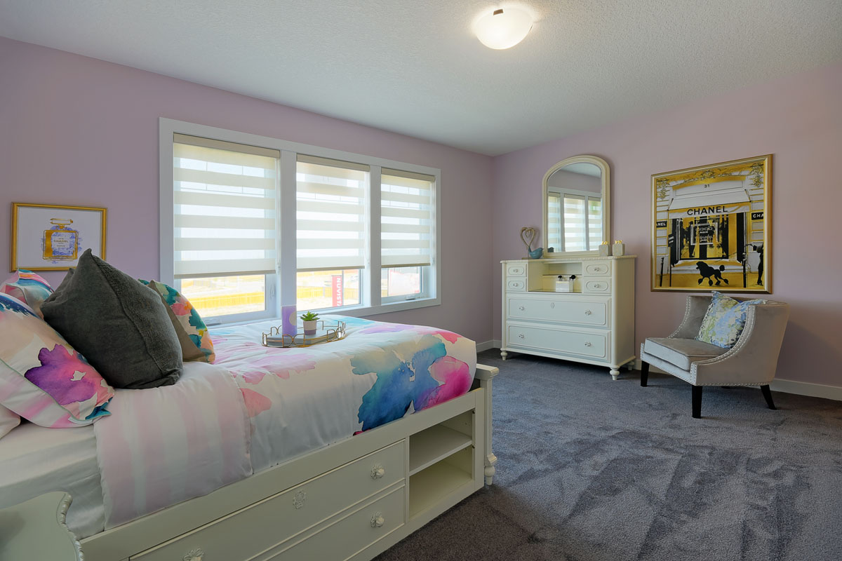 Bedroom two with a twin bed and grey carpet with three pannel window in the Brentwood model home.