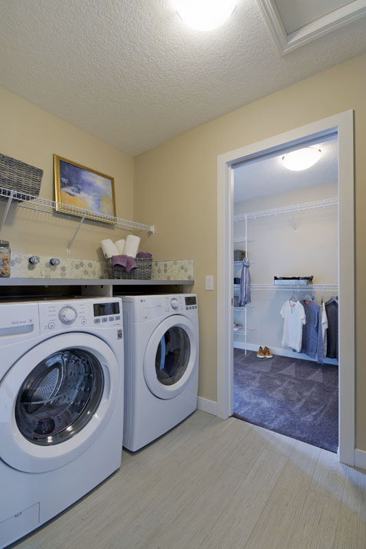 Laundry room in the Brentwood model home with two white LG washing machines and a countertop built above them.