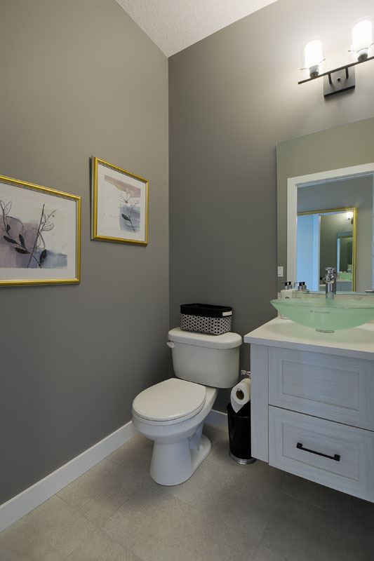 Powder room with grey painted walls and a white vanity next to the toliet in the Brentwood model home.