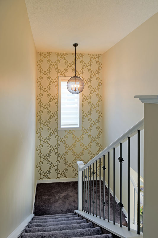 Staircase with dark grey carpet and white banister with a yellow accent wall in the Brentwood model home.
