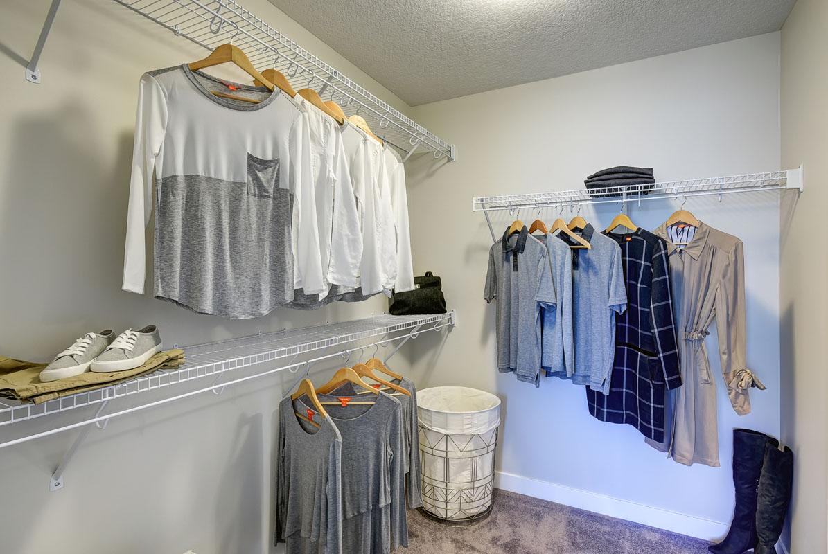 One of the walk-in closets with shirts hanging up in the Hamilton Wil model home from Nuvista Homes.
