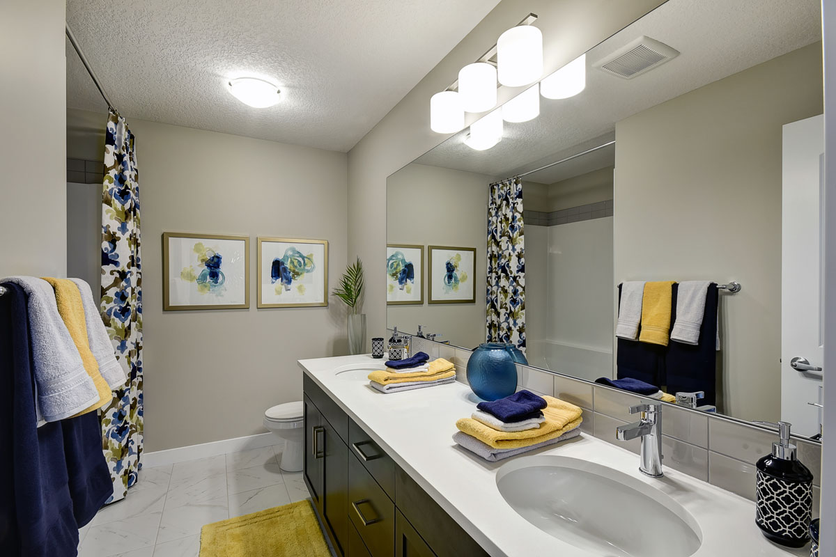Bathroom with yellow mat and floral shower curtian in the Inverness Red model home.