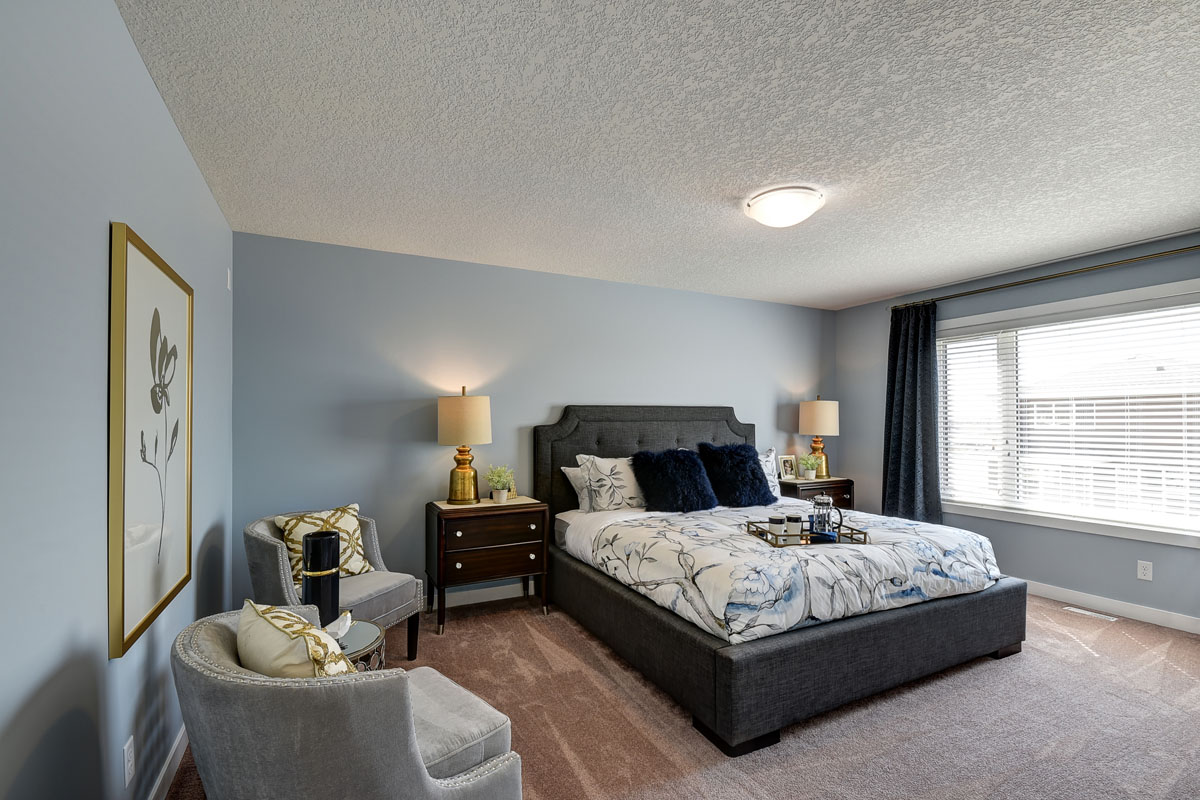 Master bedroom with queen size bed and nightstands in the Inverness Red model home.