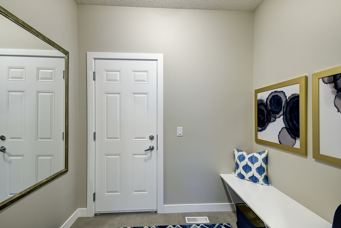 Mudroom with large mirror and white bench in the Inverness Red model home.