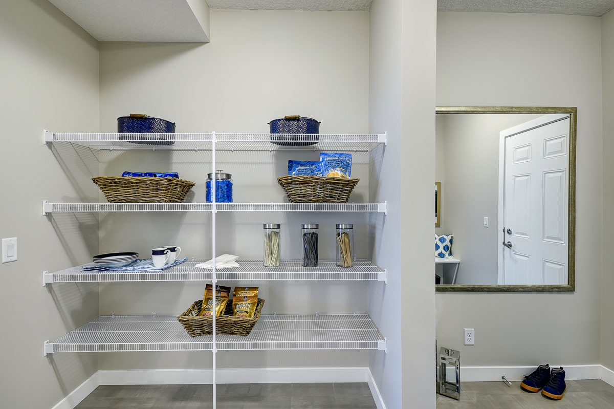 Pantry with cooking supplies on white shevles in the Inverness Red model home.