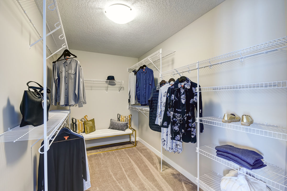 Walk in closet in the Inverness Red model home with womens clothes hanging up.