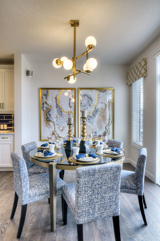 Dinning room with round glass table and six blue chairs in the Kingsley Cre model home.