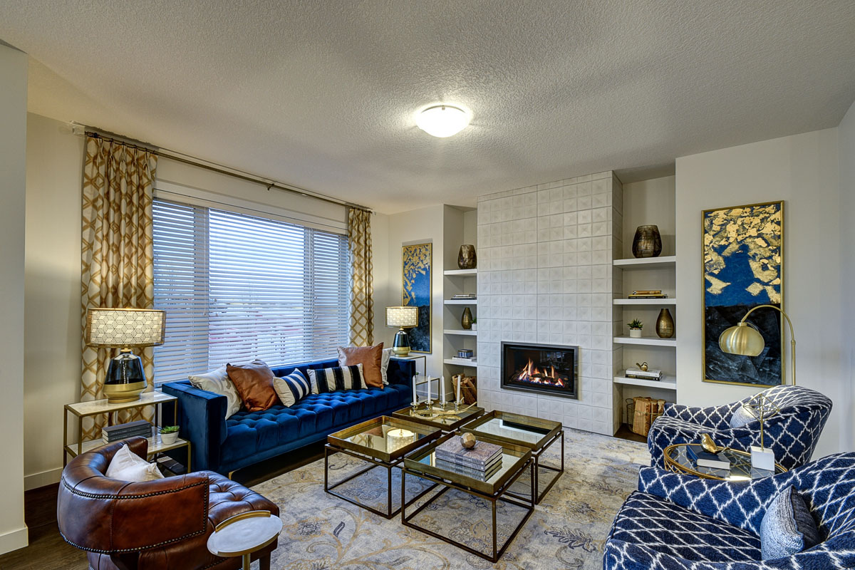 Side shot of the living room with blue couch and yellow curtains in the Kingsley Cre model home.