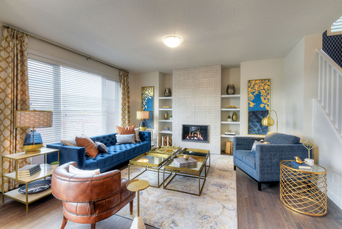 Living room with blue couch and matching blue chair next to four square glass tables in the Kingsley Cre model home.
