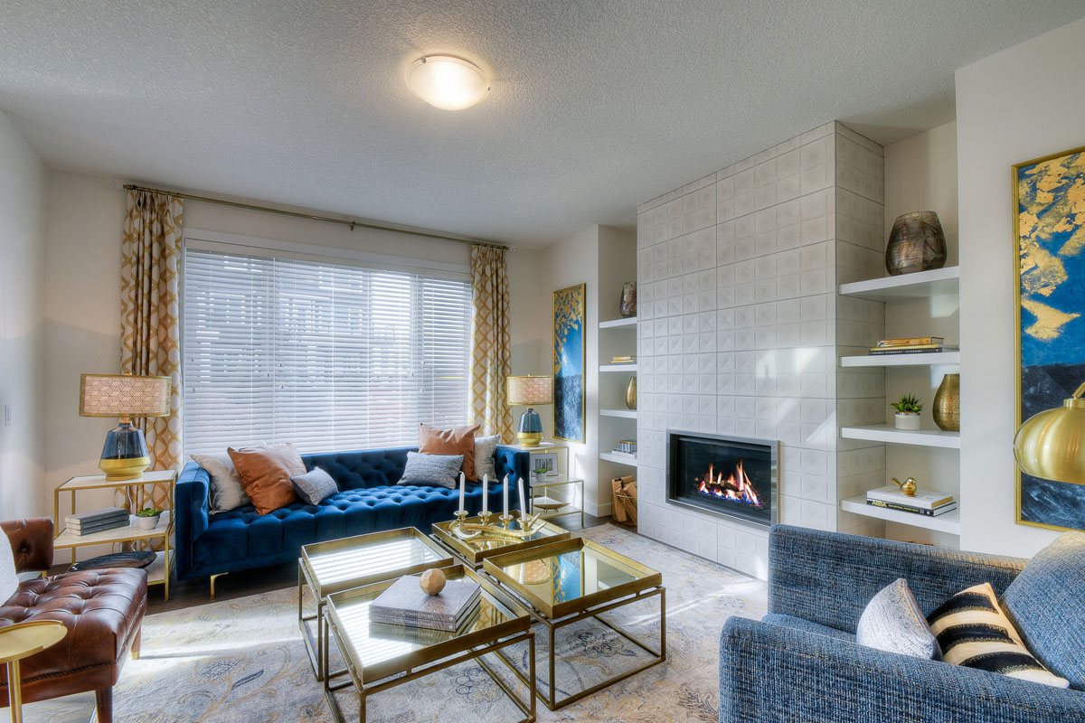 Living room with lit fire place and square glass tables in the Kingsley Cre model home.