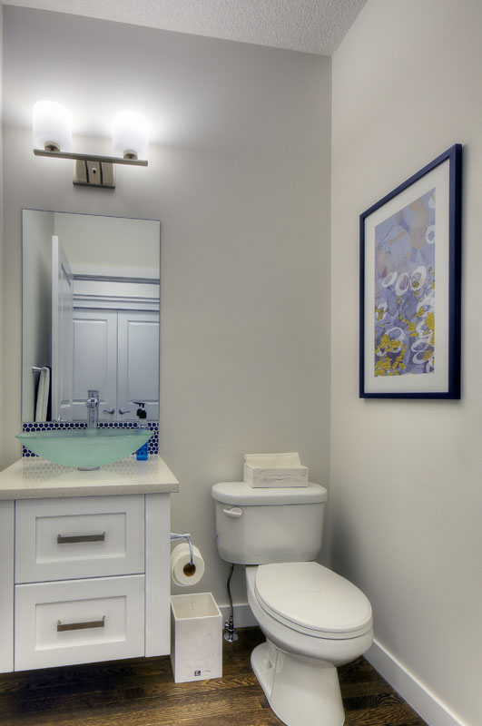 Powder room with white vanity and glass sink in the Kingsley Cre model home.