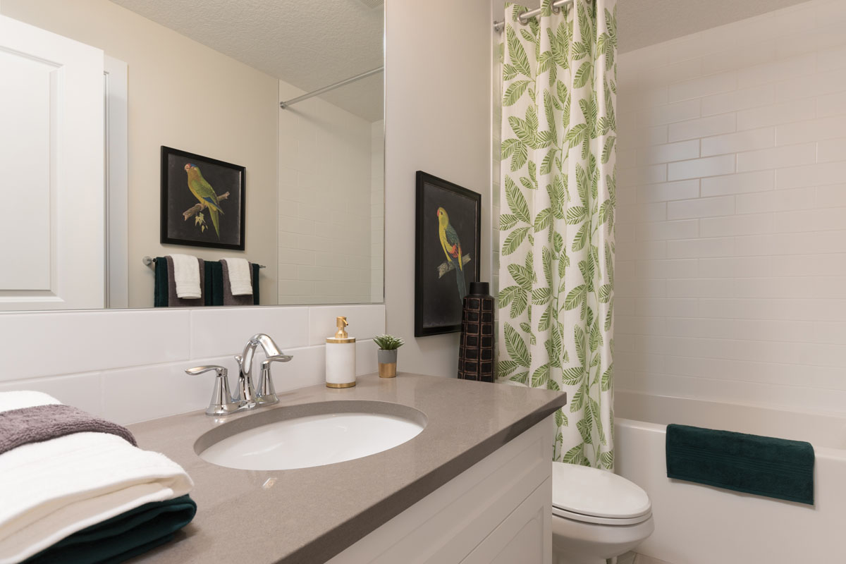 basement bathroom in the Kingston model home with green shower curtain and white vanity.