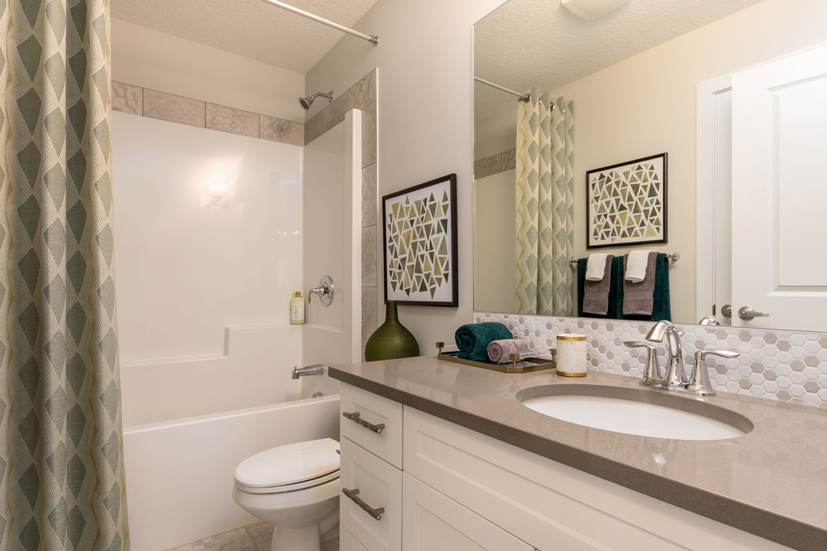 bathroom in the Kingston model home with white vanity and green shower curtain.