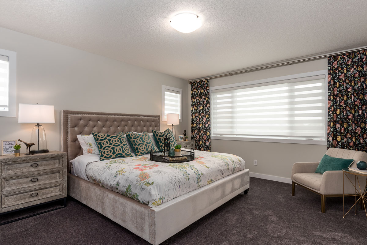 Master bedroom with dark grey carpet and king sized bed in the Kingston model home.