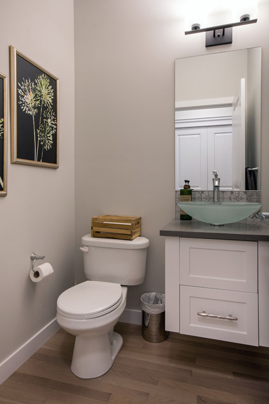 Powder room with white floating vanity and tan wood plank flooring in the Kingston model home.