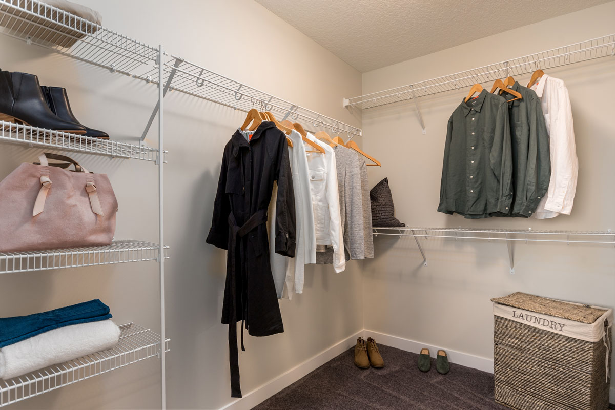Walk in closet with womens blouse hanging up in the Kingston model home from Nuvista Homes.