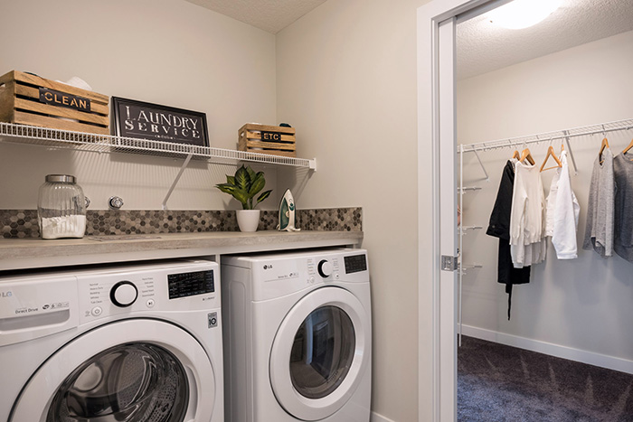 Laundry room with white LG washer and dryer and decrotive laundry service sign in the Kingston model home.