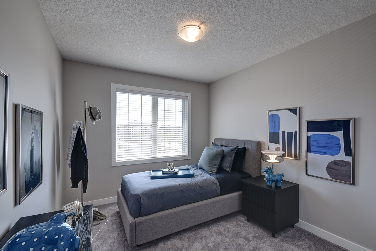 Bedroom two of the Kirkwood model home with navy and dark navy bedding next to a black nightstand.