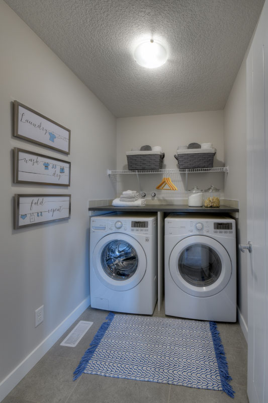 Laundry room with white LG washer and dryer and a blue and white woven floor mat in the Kirkwood model home.