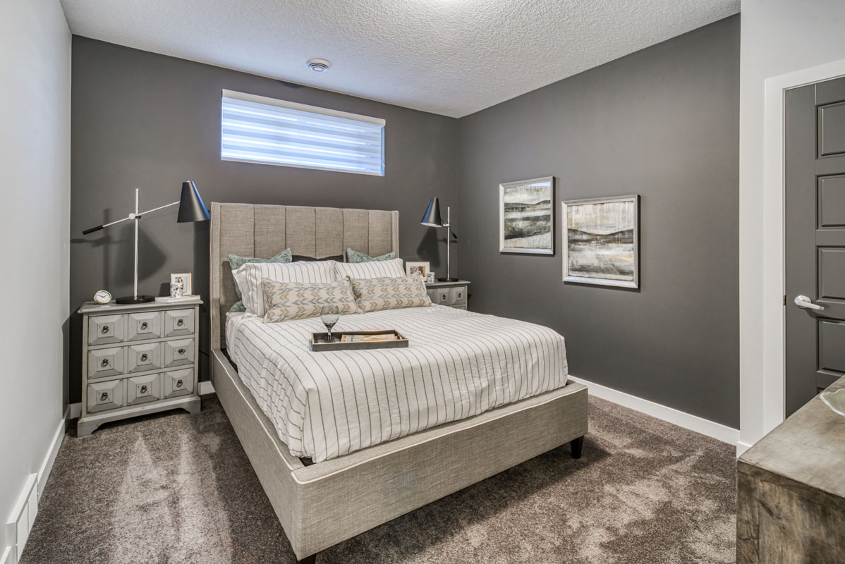 Basment bedroom with queen bed and grey painted walls in the Lakeview model home.
