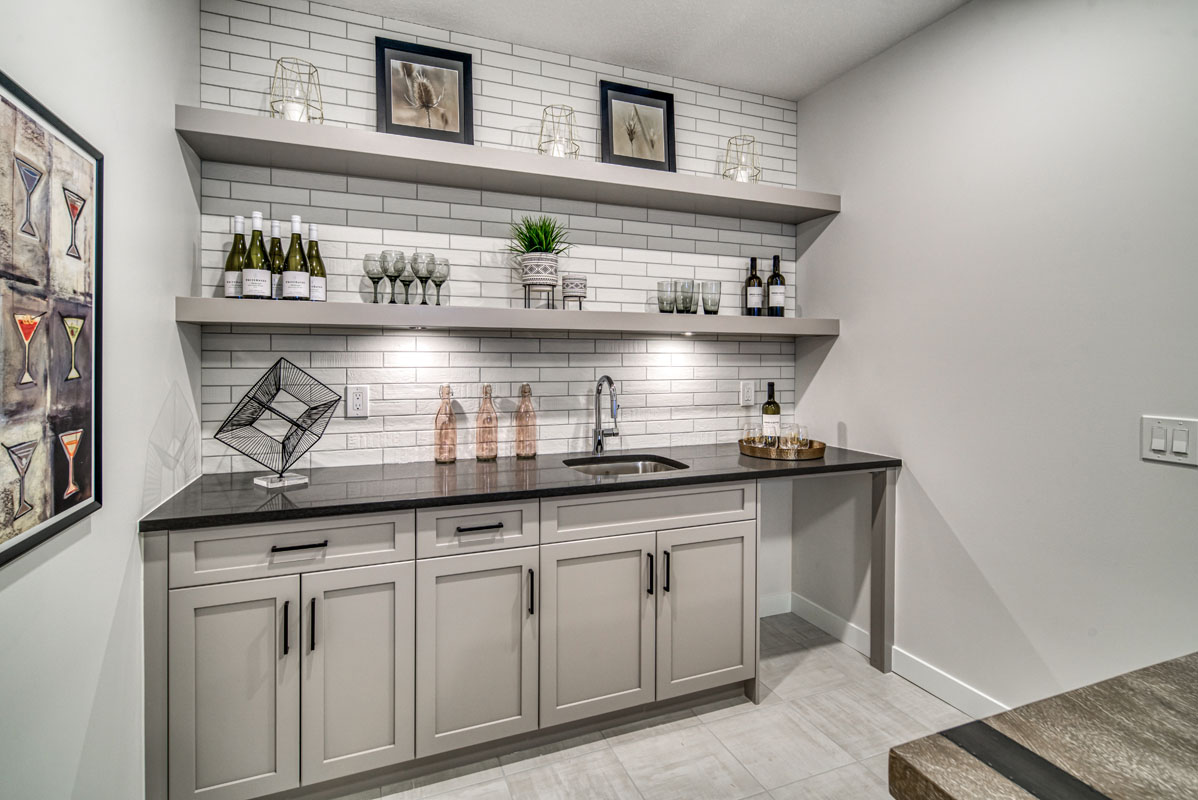 Wet bar in the basement of the Lakeview model home with white tile flooring and custom wall shelving.