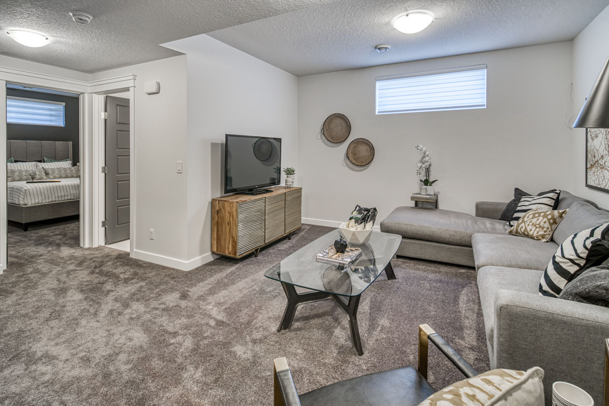 Basement living room with light grey carpet and entertainment center in the Lakeview model home.