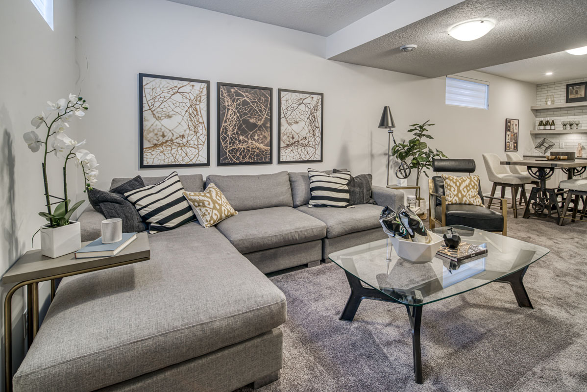 Basement living room with grey sectional and glass coffee table in the Lakeview model home.