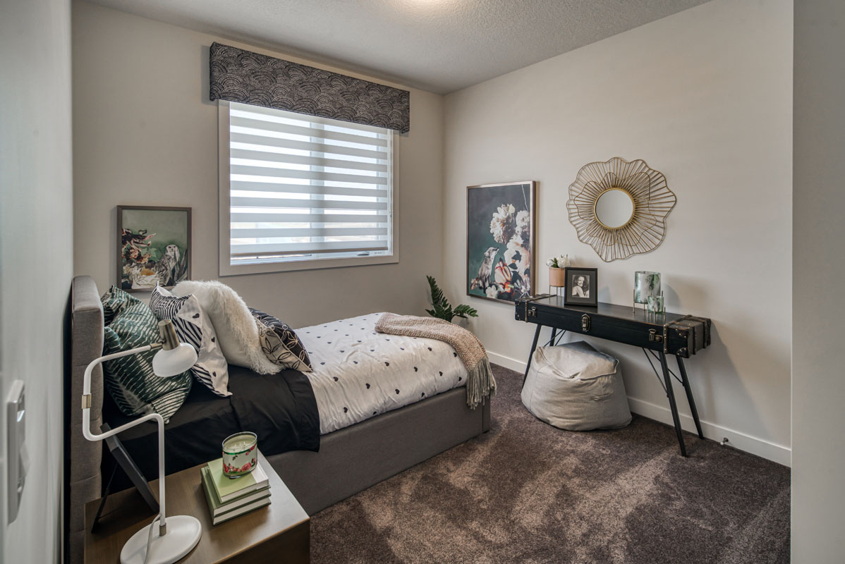 Bedroom two in the Lakeview model home with twin bed and black table on grey carpet.