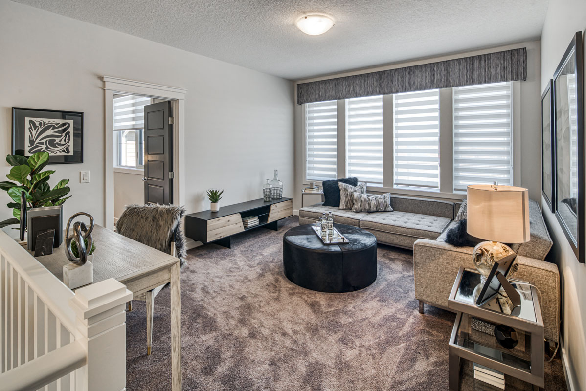 Bonus room with grey sectional and round ottoman in the Lakeview model home.
