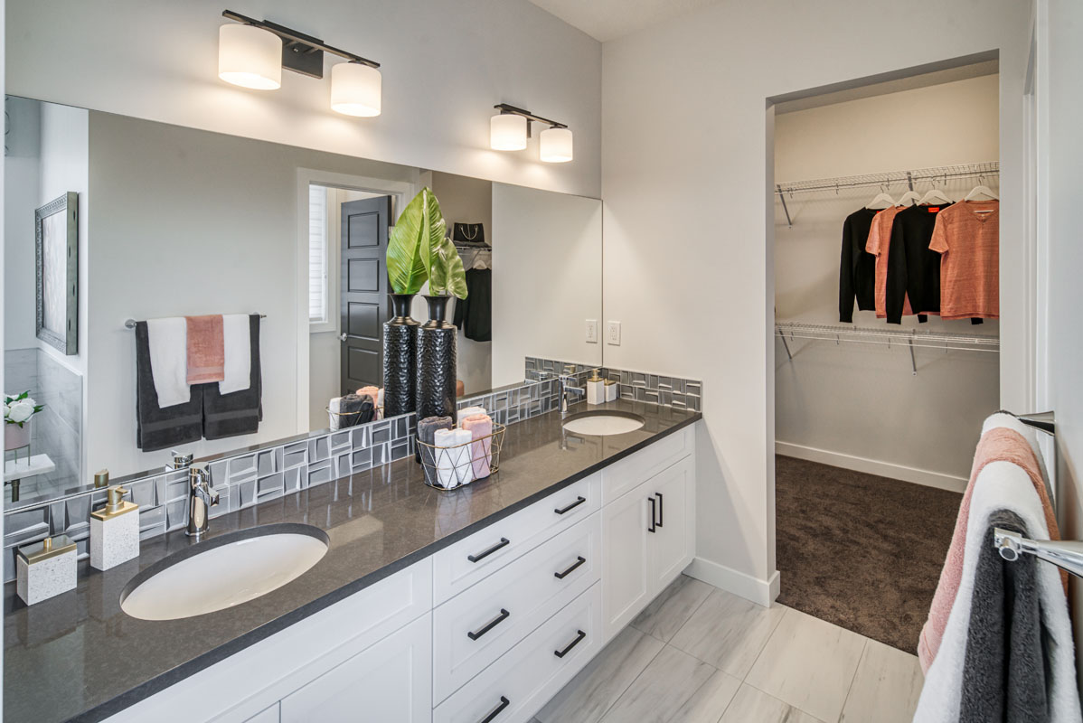 Ensuite bathroom in the Lakeview model home with double white vanity and grey and salmon towels.