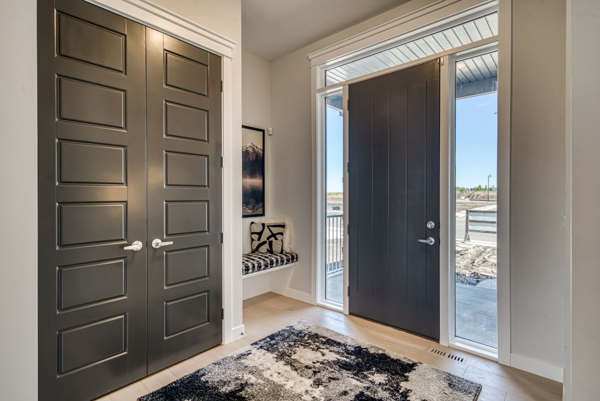 Main foyer in the Lakeview model home with large black and white mat and grey closet doors.
